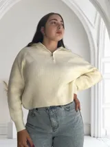 Sweater de punto color crudo con cuello polo y cierre metálico.