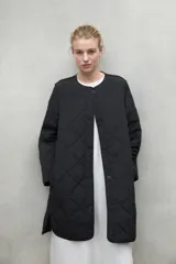 Chaqueta acolchada negra con patrón de rombos, cuello redondo y cierre frontal con botones a presión.