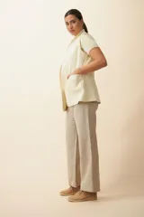 Chaleco color beige, entallado, con solapa, bolsillos plaqué y terminaciones envivadas.