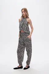 Pantalón slouchy de viscosa con estampado floral en tonos beige y negro, bolsillos laterales, cintura alta y detalle de punto smock en los tobillos.
