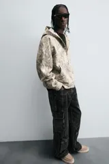 Pantalón relaxed fit de denim negro con efecto lavado, bolsillos frontales, traseros de plastrón y multifunción en perneras. Bajo ajustable con trabilla y cierre frontal con cremallera y botón.