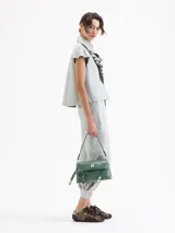 Camisa de cuero ovino negra, con volados en el centro delantero, mangas con volumen fruncidas en la copa y broches forrados en cuero.