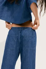 Pantalón de jean azul con cintura elástica ajustable con cordones, tiro medio y bolsillos de parche en la parte trasera.