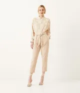 Camisa de crepé color beige con estampado geométrico en tonos neutros, cuello camisero, manga larga y cierre con botones. Tiene un lazo frontal para atar.