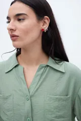 Blusa verde con escote en V, cuello camisero, manga corta y dos bolsillos en el pecho.