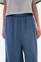 Pantalón capri de denim azul con cintura elástica y aberturas laterales en el ruedo.