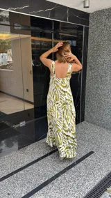 Vestido largo estampado con escote en V profundo y tirantes anchos. El diseño presenta un frunce o nudo en el centro del busto y tajos laterales en la falda.