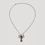 Collar con cadena de eslabones plateada y dije con forma de la muerte con capucha y dos guadañas.