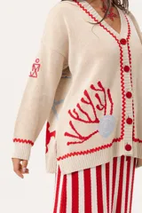 Saco oversize tejido con ilustraciones inspiradas en corales, peces, estrellas de mar y tortugas. Presenta galón picot en rojo en cartera y puños, y botones a tono.