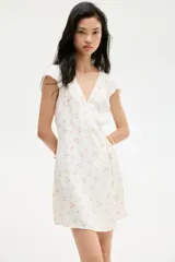 Vestido corto de crepé de viscosa con estampado floral, escote en V y manga japonesa. Tiene frente cruzado con tiras para atar, cuerpo entallado y falda con leve vuelo.