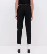 Pantalón cigarrete negro de algodón con cinturón fino marrón.