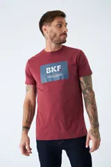 Remera de algodón color bordó con estampado rectangular azul con letras blancas en el frente.