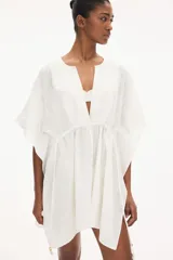 Túnica playera blanca de manga corta con escote en V y cordones ajustables en la cintura.
