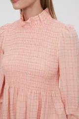 Blusa color salmón con estampado a cuadros, cuello alto fruncido, mangas largas abullonadas con puños elásticos y corte peplum.