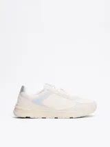 Zapatillas deportivas Tommy Hilfiger de corte bajo, color blanco con detalles en celeste y plateado. Presentan paneles de malla y superposiciones de gamuza, con el monograma TH en la lengüeta y el lateral.