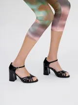 Sandalias de charol negro con tiras finas cruzadas en el empeine, pulsera al tobillo con hebilla y tacón cuadrado.