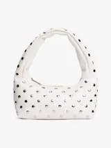 Bolso de hombro blanco con forma curva y correa corta. El cuerpo del bolso está decorado con tachuelas metálicas redondas plateadas. Posee cierre superior con cremallera.