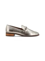 Zapato mocasín plateado de cuero metalizado, con hebilla metálica decorativa, forro y plantilla de cuero, y suela de goma.