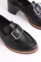 Mocasín de cuero color marrón con hebilla metálica plateada y taco de madera.