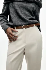 Pantalón negro de tiro alto con pernera recta, bolsillos frontales y falsos bolsillos con solapa en la espalda. Incluye cinturón marrón de cuero sintético.