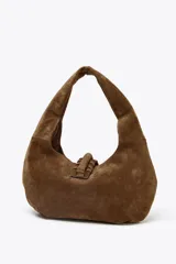 Bolso de hombro marrón de serraje con asa corta y flecos decorativos.