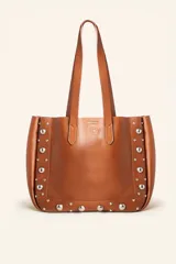 Bolso tote de cuero color marrón con tachas plateadas en los laterales. Tiene doble asa de hombro y un sobre interior de cuero.