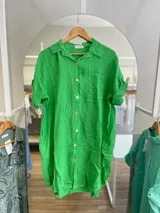 Vestido camisero corto color verde manzana, confeccionado en lino. Tiene cuello camisero, mangas cortas con trabillas y abotonadura frontal.