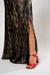 Vestido largo de fiesta con estampado abstracto en tonos dorados y negros. Tiene escote en V, corte en la cintura y aberturas laterales.