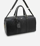 Bolso tipo valija grande color negro, con textura geométrica en relieve, cierre de cremallera, correa de mano, asa larga desmontable y tag de identificación.