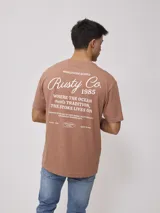 Remera color ladrillo de corte holgado, con estampa en la espalda con el logo de la marca y texto alusivo al surf.