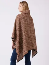 Ruana tejida de la marca Jones New York, con estampado a cuadros en tonos marrón, beige y blanco. Presenta cuello alto y cierre frontal con botón trenca y botón a presión interno. Los bordes están ribeteados en negro.