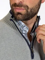 Sweater gris claro de punto con medio cierre y cuello alto.