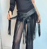 Faja de cuero sintético negro con tachas plateadas y flecos largos.