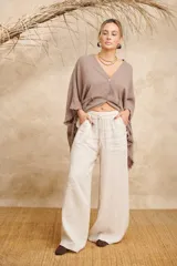 Pantalón palazzo color crudo, de lino, con cintura elastizada y bolsillos laterales desflecados.