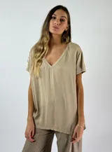 Blusa de corte suelto color beige, con escote en V y mangas cortas.