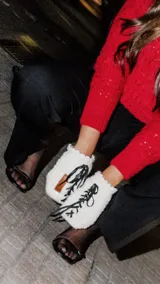 Mitones tejidos a mano en lana merino natural color crudo, con detalle de tiento de cuero negro que se ata en el centro.