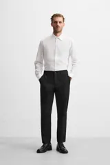 Camisa blanca de corte regular, cuello italiano, manga larga con puños abotonados y cierre frontal con botones.
