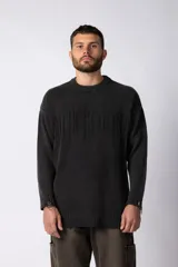 Sweater negro de algodón con cuello redondo, mangas largas, puños y ruedo acanalados con roturas. Presenta un bordado con texto en el frente.
