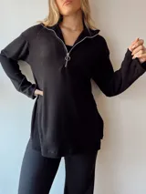 Sweater negro de punto canalé con cuello polo y etiqueta de cuero sintético en la espalda.
