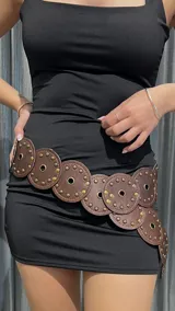 Cinturón marrón con apliques circulares y tachas doradas.