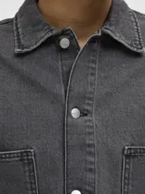 Camisa de denim negra de manga larga con cuello clásico y cierre con botones. Diseño amplio con bolsillos en el pecho.
