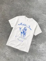 Remera blanca de algodón con cuello redondo y estampado azul con la inscripción "Habibi Joseo", la imagen de un hombre montando un camello y el número #21.