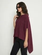 Poncho tejido de punto grueso, color mostaza/mostaza oscuro, con cuello redondo y caída amplia.