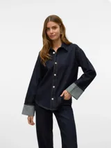Camisa de denim azul oscuro con cuello clásico, manga larga con puños en denim gris claro y cierre frontal con botones plateados.