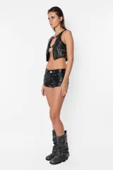 Short negro de cuerina con tiro bajo, presillas anchas con remaches, bolsillos delanteros rectos y traseros con recorte y remaches.