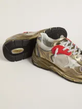 Zapatillas deportivas Golden Goose modelo Running Dad, con diseño moderno y efecto desgastado. Combinan cuero dorado, malla blanca y detalles en gris y rojo. Presentan la estrella distintiva de la marca en blanco y suela robusta.