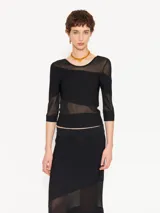 Top negro de fit al cuerpo, largo hasta la primera cadera y mangas 3/4. Combina tejido con organza transparente.