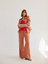 Camisa blanca de lino con cuello clásico, abotonada al frente con botones de madera, mangas largas con volados en los hombros y corte femenino.