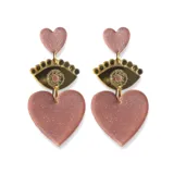 Aros grandes en forma de corazón color beige con detalles dorados y diseño de ojo.