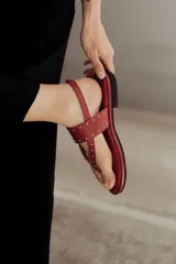Sandalias marrones de cuero con tiras, microtachas doradas y hebilla lateral.